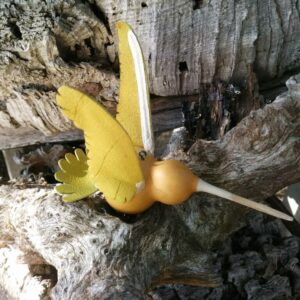 A carved gourd resembling a hummingbird sits displayed on a wood burl