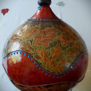 A large decorative gourd that has been carved and painted to look like leaves