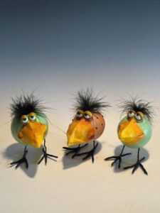 Three carved gourds resembling chicks sit displayed on a table