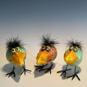 Three carved gourds resembling chicks sit displayed on a table